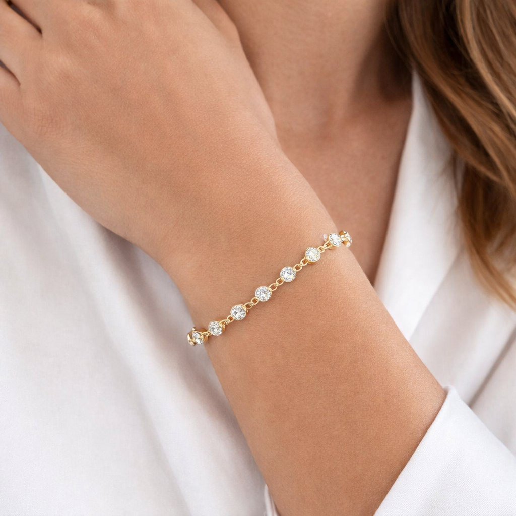 Gold bracelet with small diamonds on a person's wrist against a white background