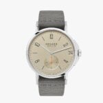 Luxury NOMOS Glashütte watch features a minimalist design with a sandy dial and olive green strap.