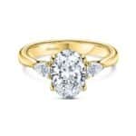 Elegant yellow gold engagement ring featuring an oval diamond and pear-shaped side stones.