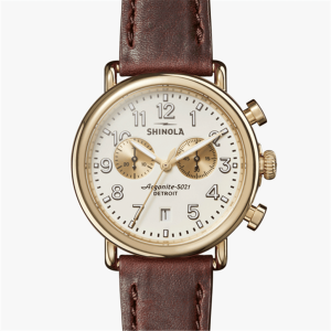 Shinola gold-tone wristwatch with white dial, chronograph, and brown leather strap for elegant style.